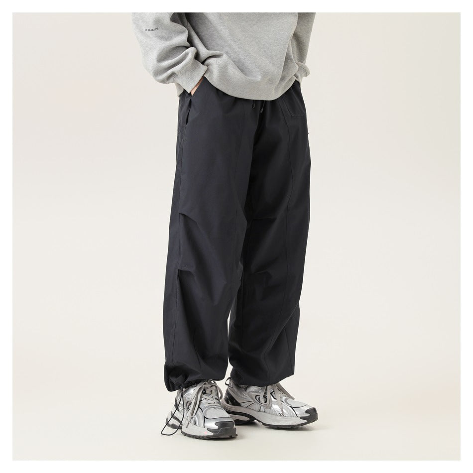 Model wearing loose black pants with a drawstring waist and wide legs, shown from the front at an angle.