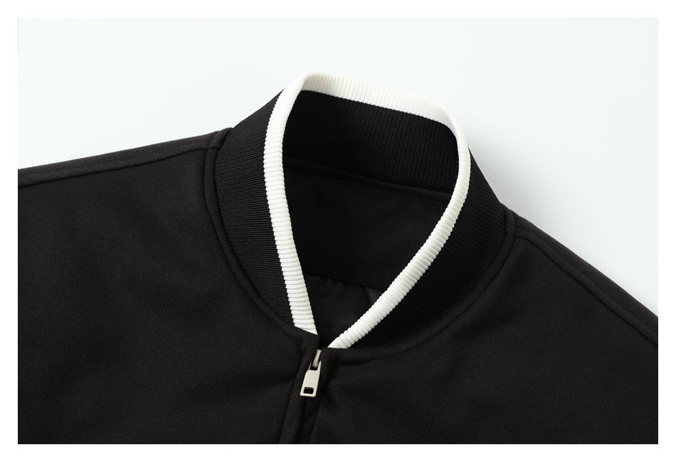 Close-up of a black jacket's ribbed stand collar with white trim and a silver zipper pull.