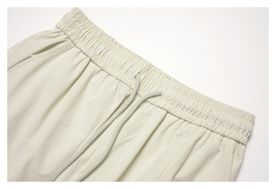 Close-up of the off-white pants' gathered elastic waistband and braided drawstring.
