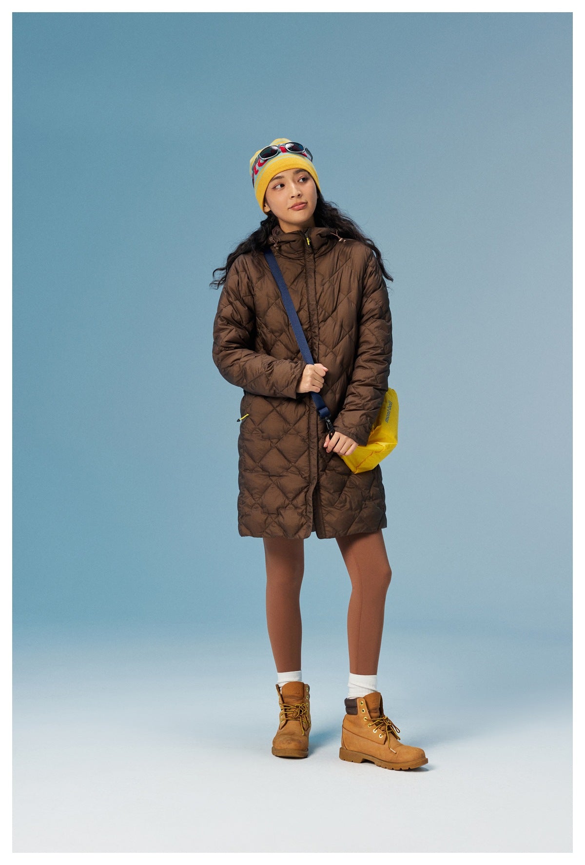Full-length front view of a model wearing a brown quilted hooded coat.
