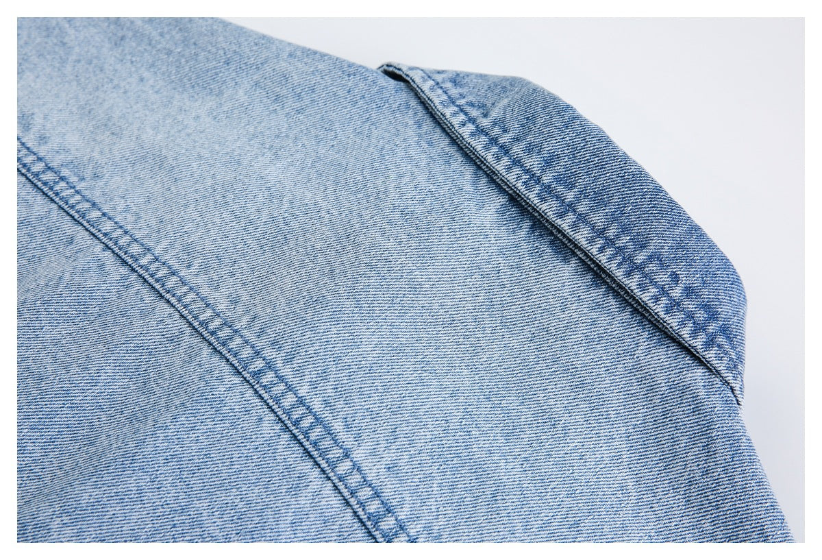 Close-up of light blue denim with diagonal seams and a folded edge.
