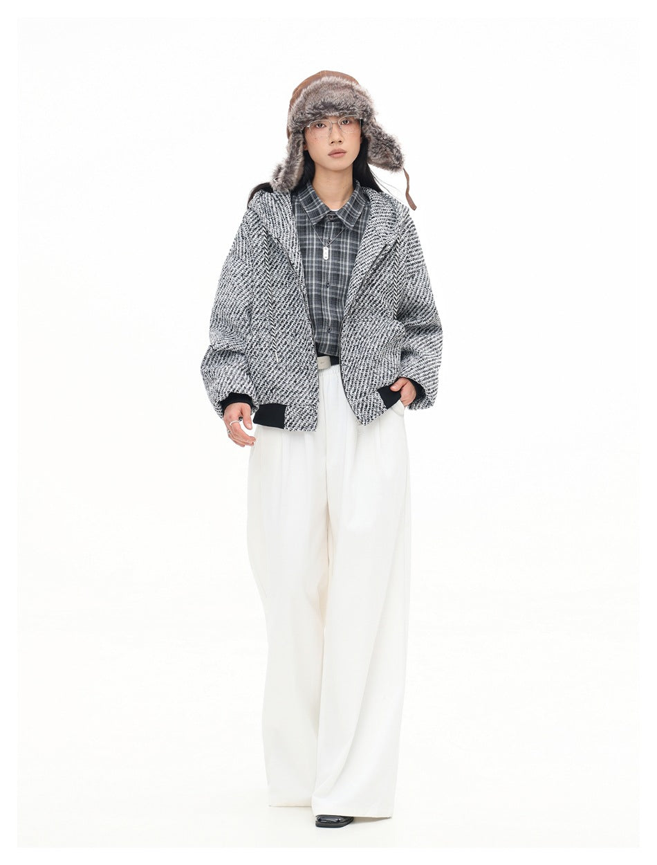 Full-length front view of a model wearing an open black-and-white textured hooded jacket and wide white trousers.