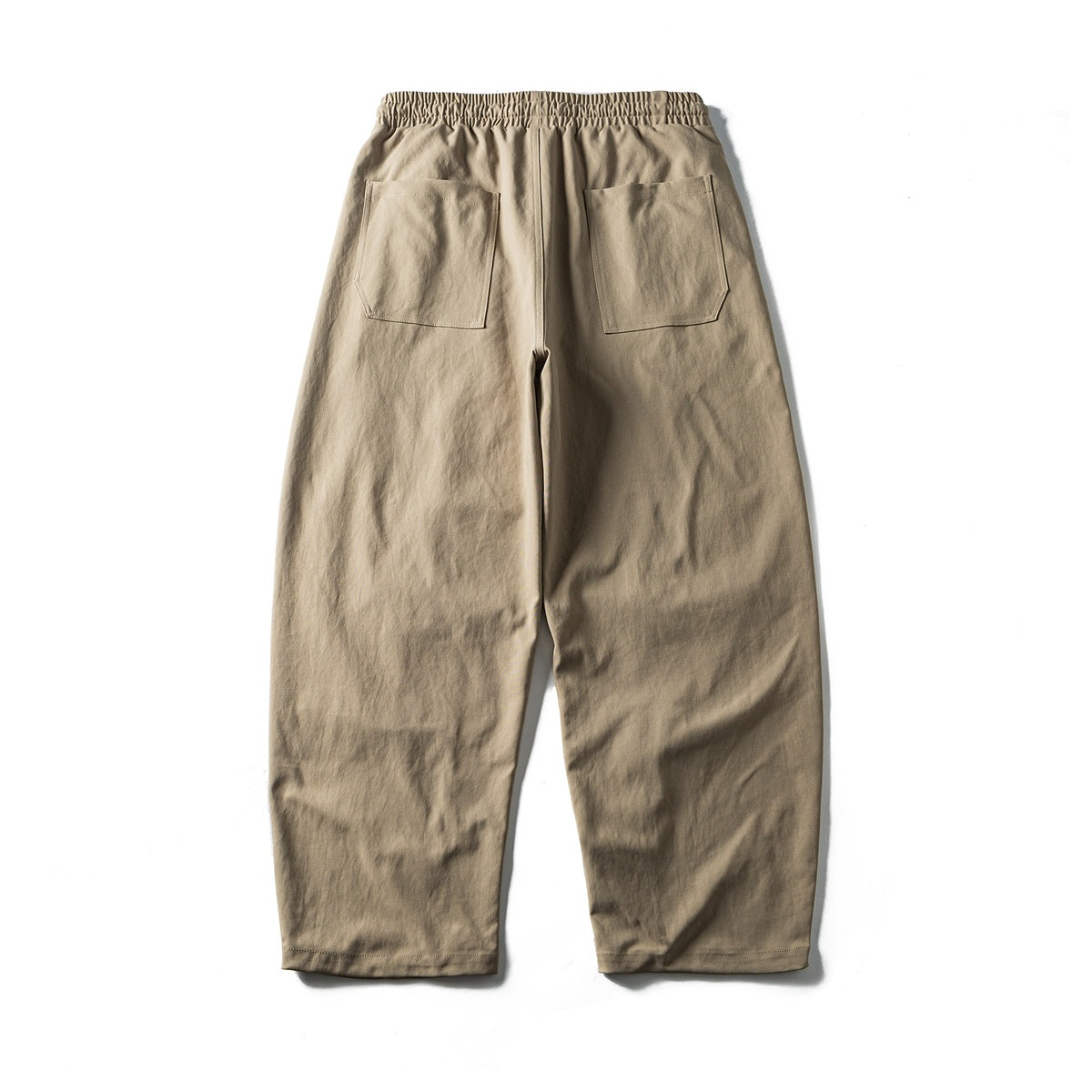 Back view of taupe loose trousers with an elastic waistband and two patch pockets.