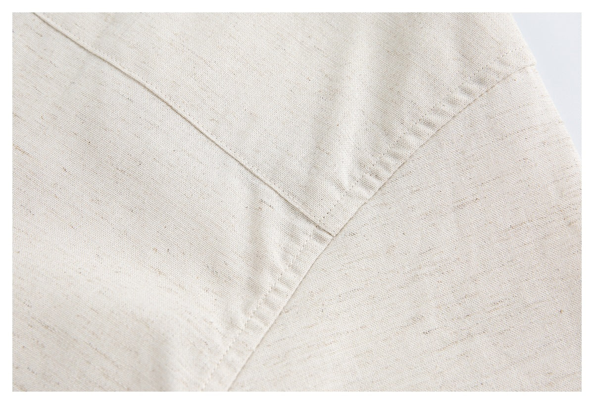 Close-up of light beige, subtly speckled fabric showing a stitched seam and intersecting edges.