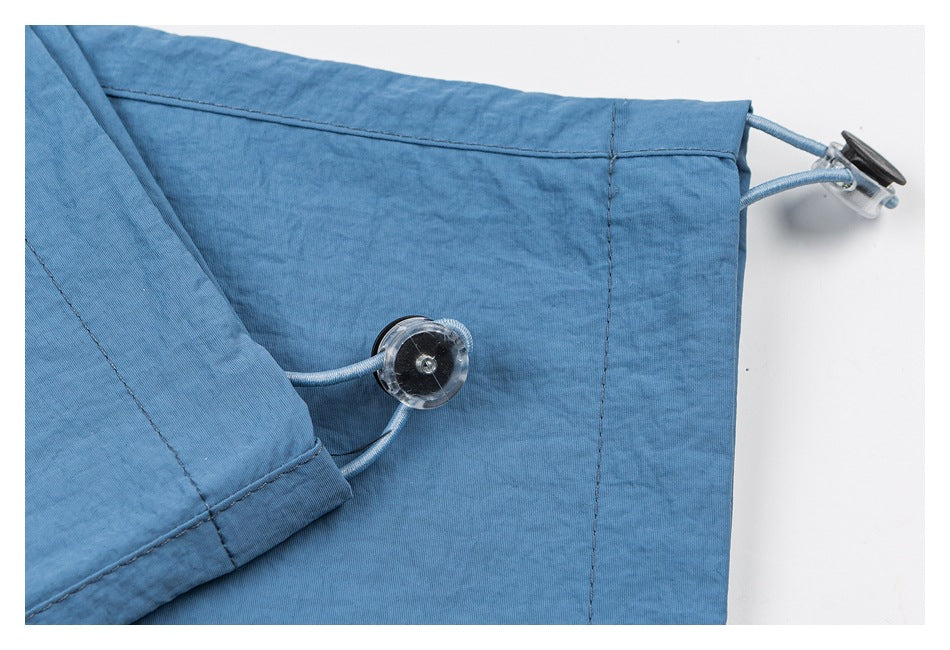Close-up of blue shorts showing a cord-and-toggle adjustment detail at the hem.