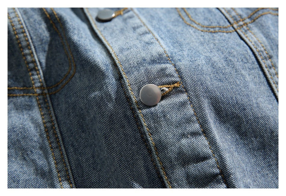 Close-up of a silver snap button and stitching on the front placket of a blue denim jacket.