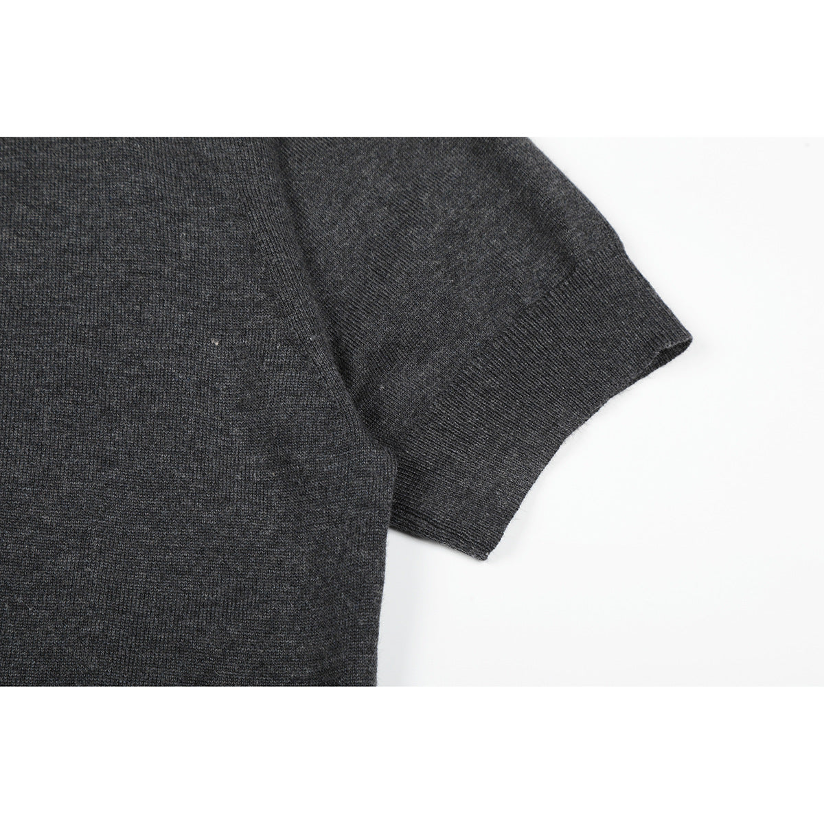 Close-up of a charcoal knit top's short sleeve and ribbed cuff.