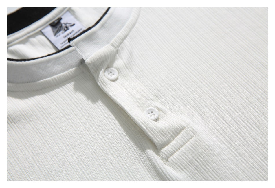 Close-up of the white ribbed henley shirt's two-button placket and collar trim.
