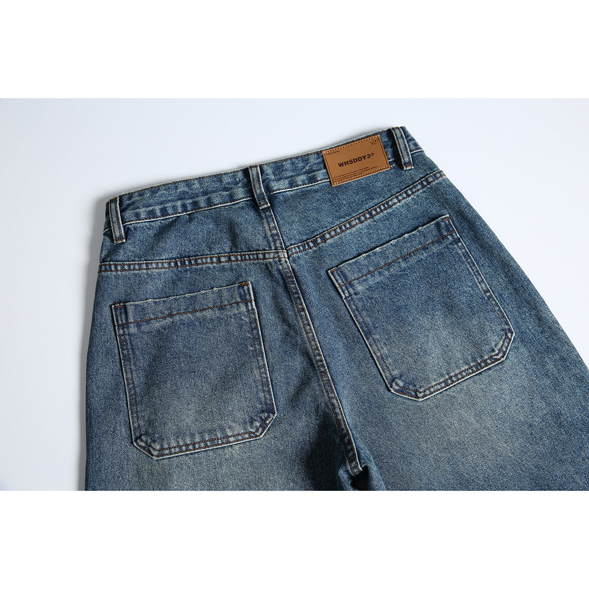 Back view of blue-wash jeans showing two patch pockets, belt loops, and a brown waistband label.
