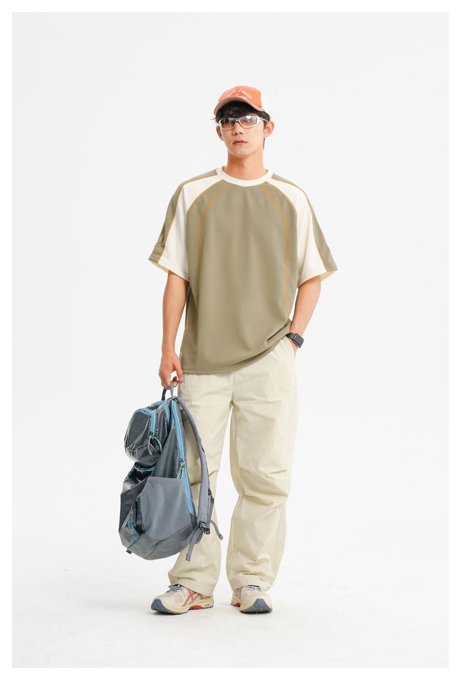 Front view of a model wearing an olive-and-cream raglan T-shirt with loose cream trousers.