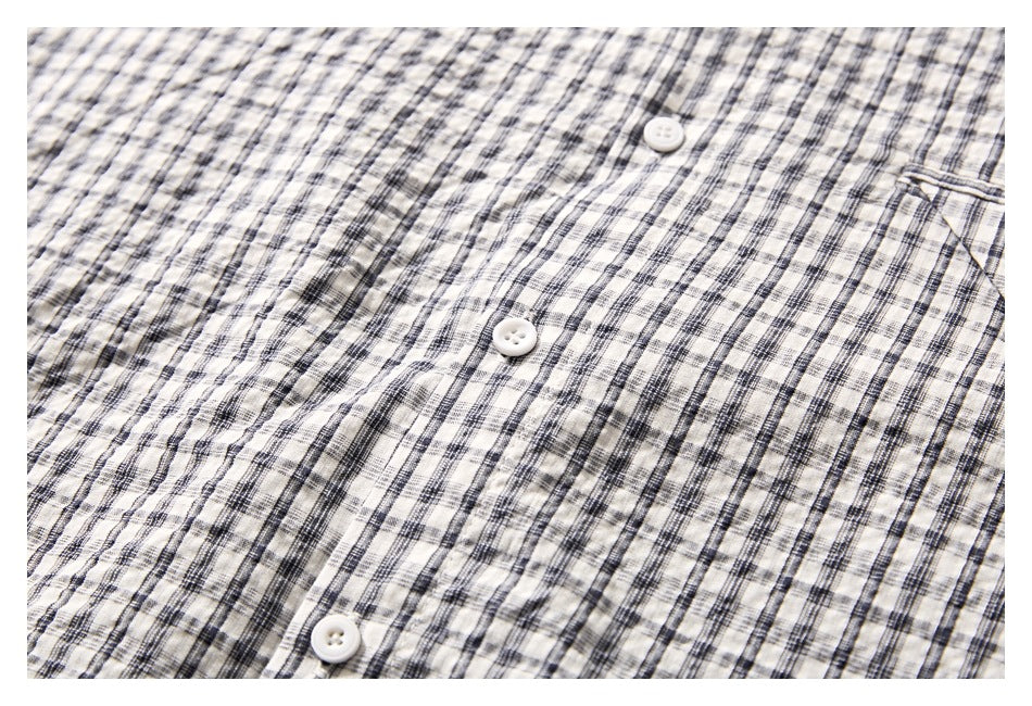 Close-up of white buttons and black plaid on the cream shirt front.