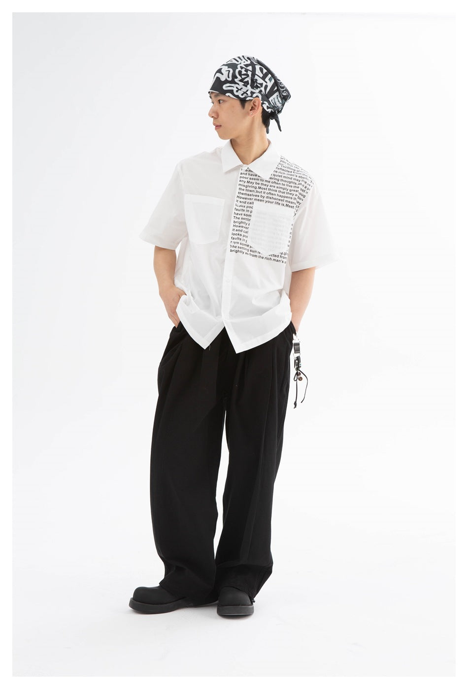 Model in black wide-leg pleated trousers, white short-sleeve printed shirt, bandana and black chunky shoes