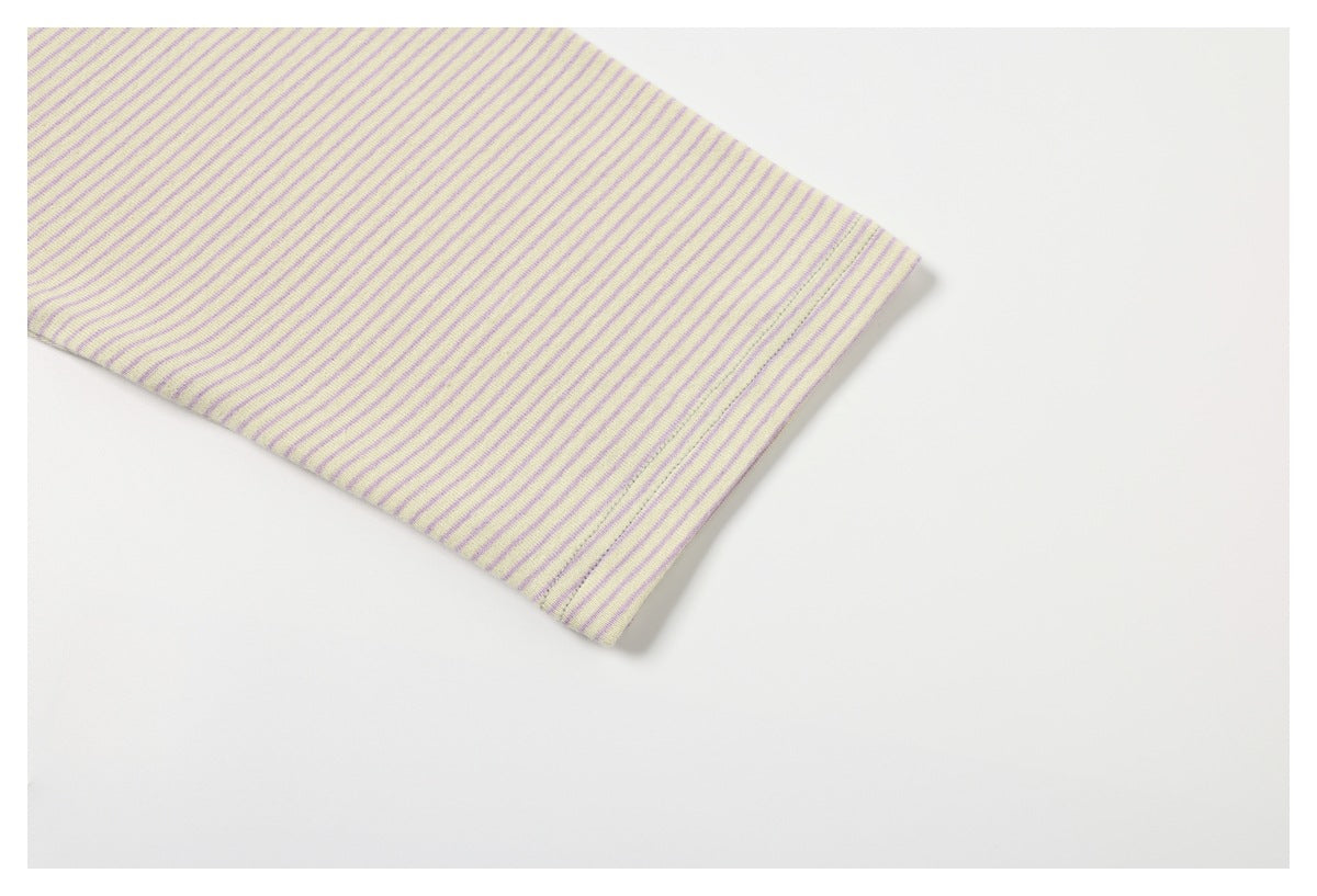 Close-up of a pale yellow garment cuff with narrow purple stripes and a finished edge.