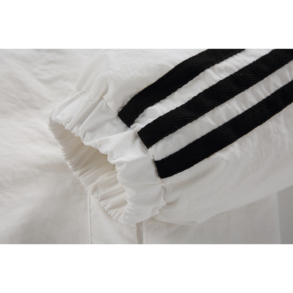Close-up of a white jacket sleeve with three black stripes and an elastic cuff.
