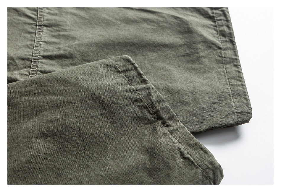 Close-up of olive pants fabric and stitched hem on a white background.