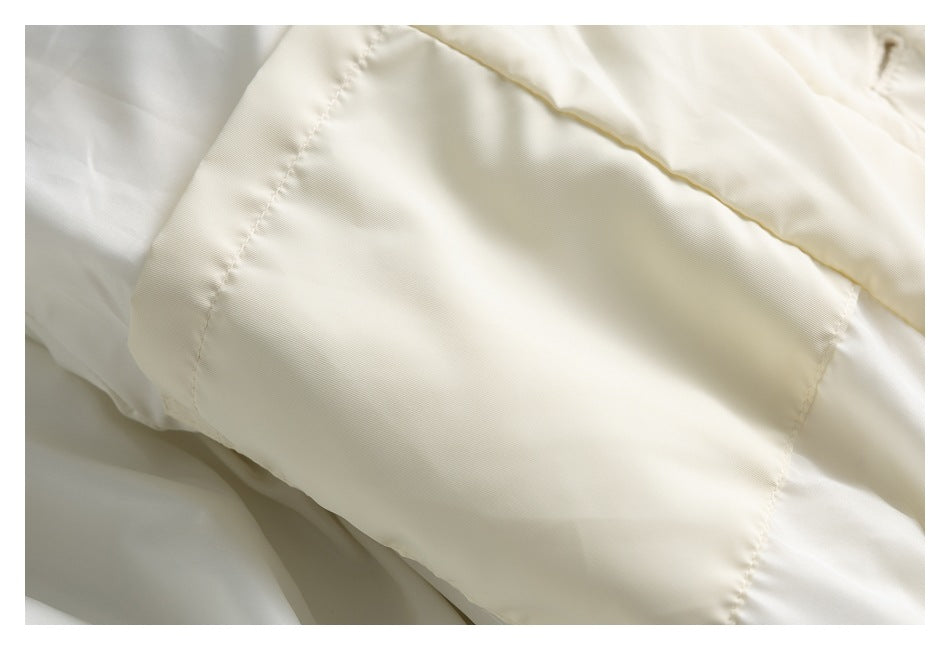 Close-up of a curved stitched panel on a pale cream garment.