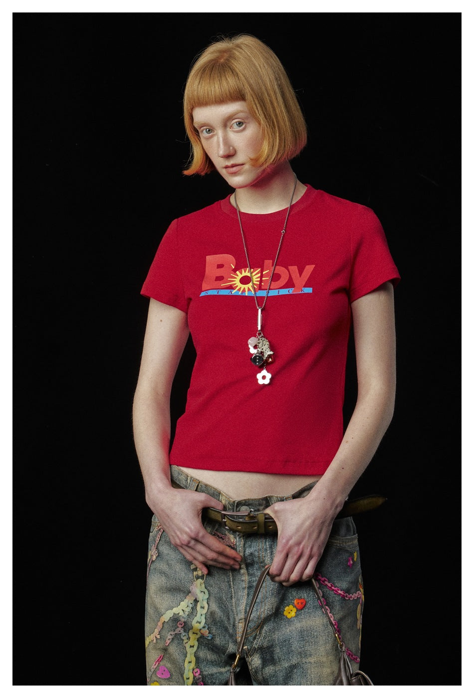 Waist-up view of a model in a red graphic T-shirt with a crew neckline and short sleeves.