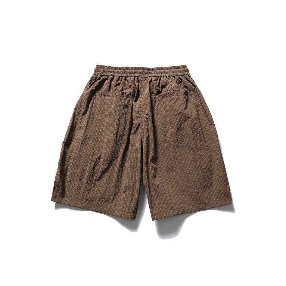 Back view of brown check shorts laid flat, with an elastic waistband and two rear pockets.