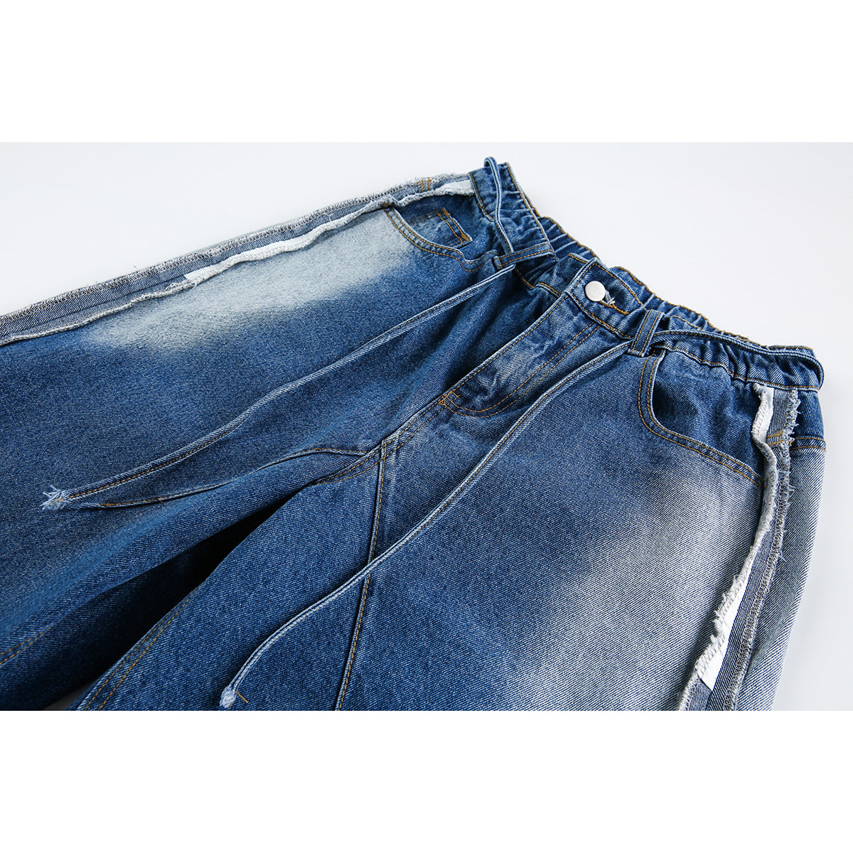 Close-up of blue denim shorts showing the waistband, button, front pocket, and contrasting faded panels.