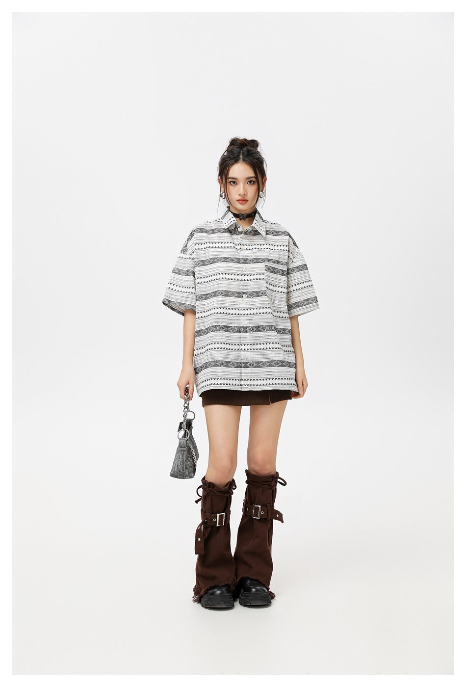 Model wearing an oversized white button-up shirt with black geometric stripe patterns and a brown mini skirt.