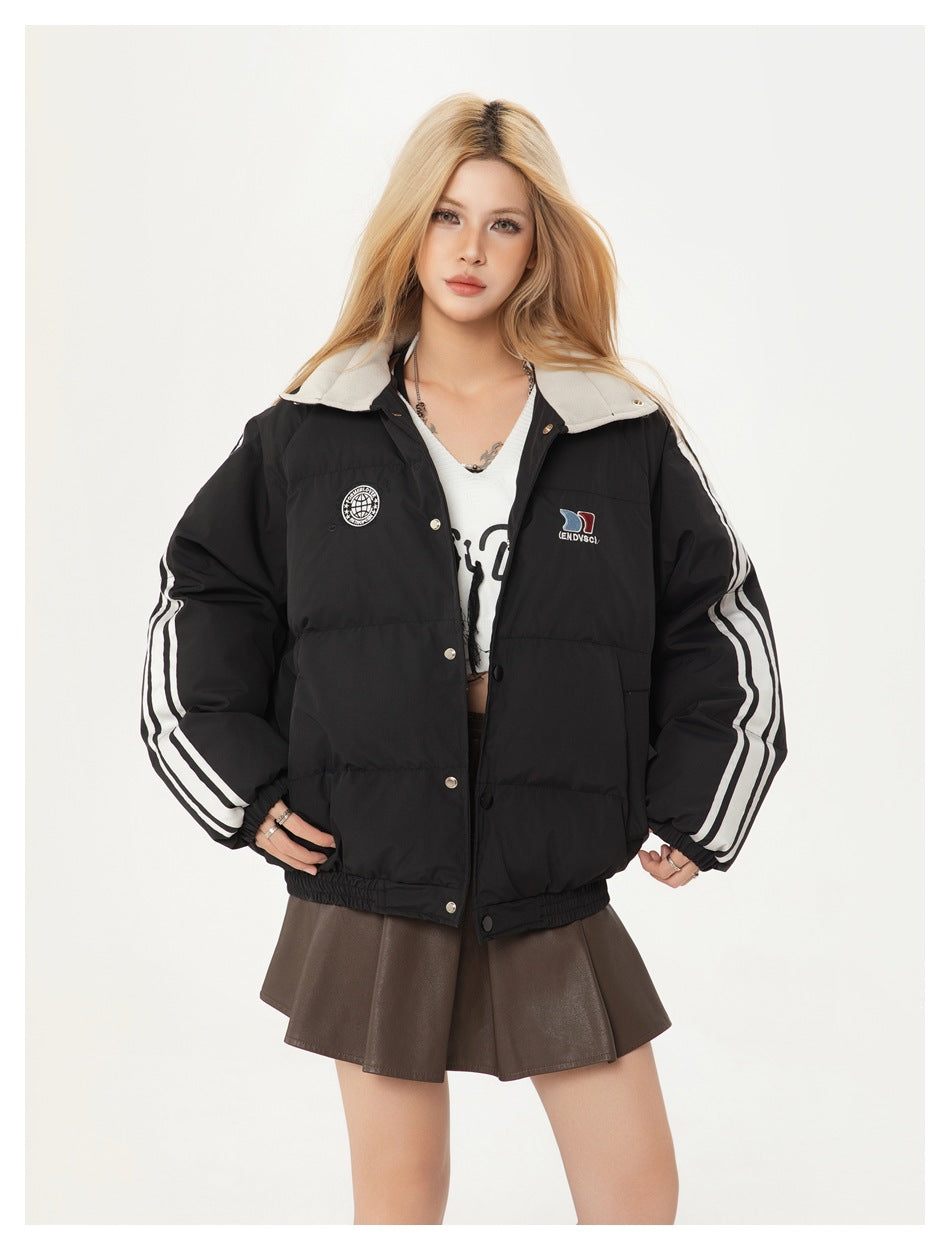 Model wearing a black quilted jacket with a light collar, white sleeve stripes, chest patches and snap buttons.