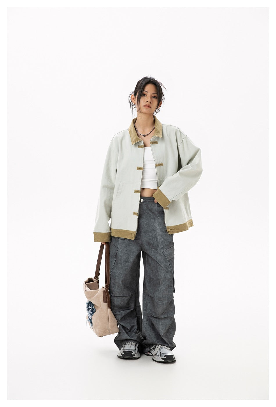 Full-length model wearing a pale gray jacket with tan trim and toggle closures, paired with dark cargo pants.