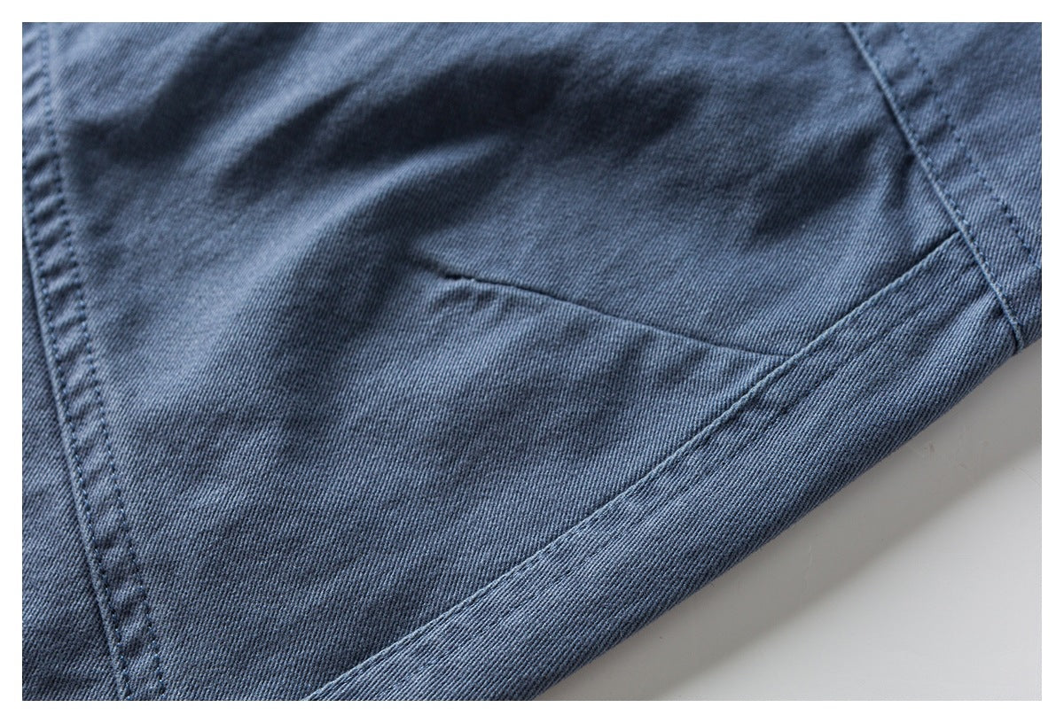 Close-up of blue pants showing a stitched pocket and hem edge.