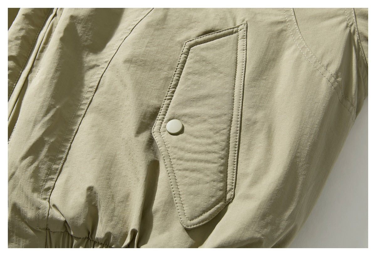 Close-up of an olive-khaki jacket’s flap pocket with a light-colored snap.