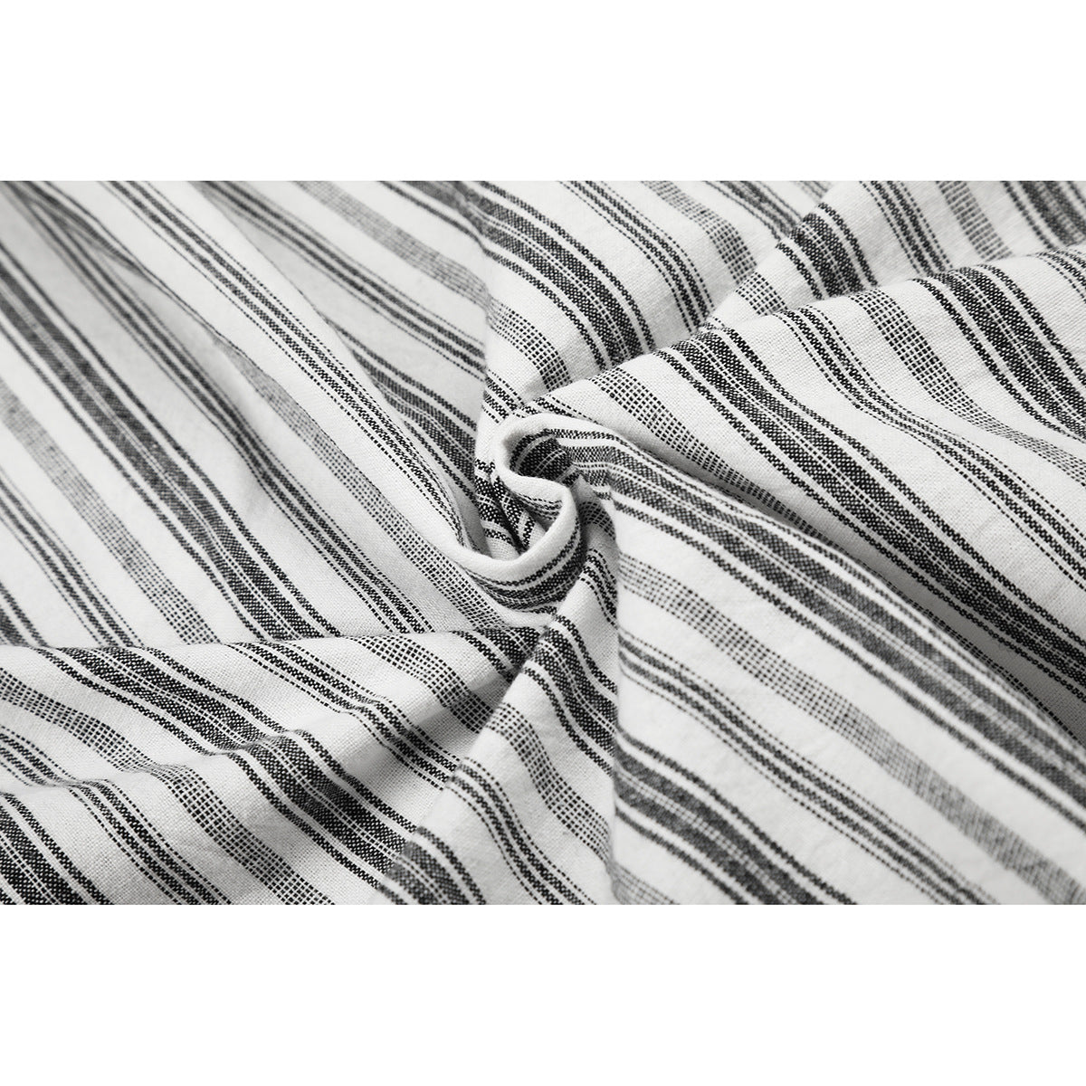 Close-up of white fabric with varied black stripe patterns, gathered to show its texture and drape.