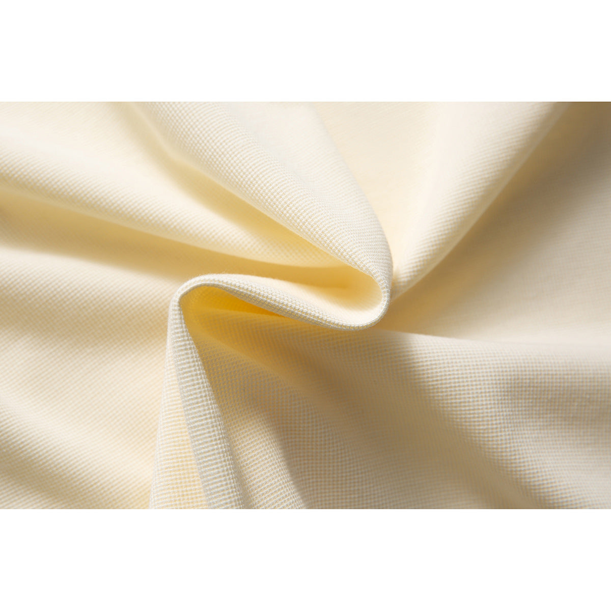 Extreme close-up of ivory textured polo fabric gathered into soft folds.