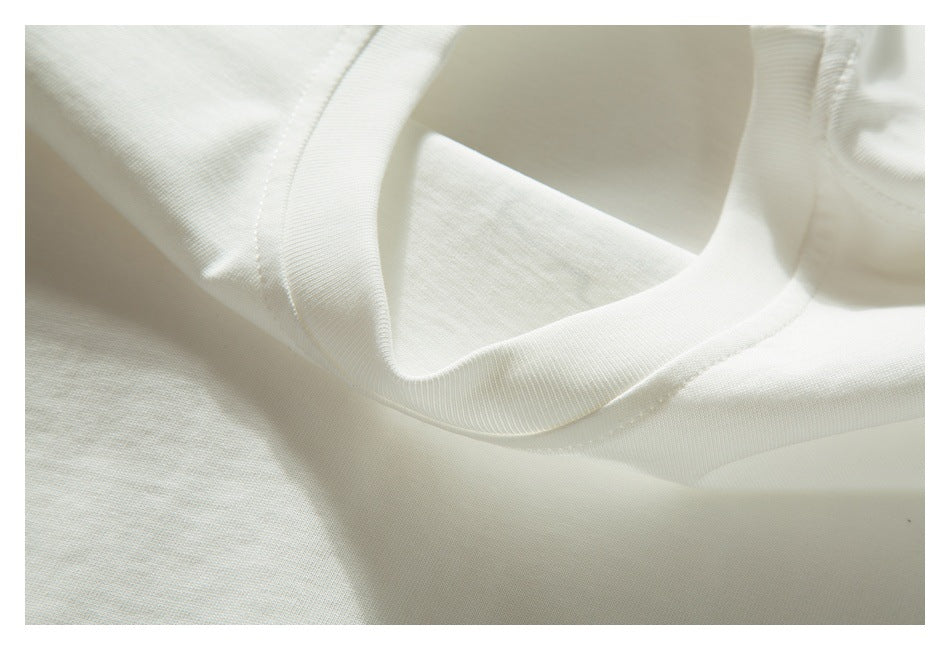 Close-up of the ribbed crew neckline and shoulder seam of an off-white T-shirt.