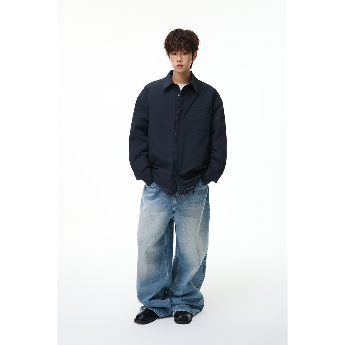 Full-length view of a model wearing an oversized dark navy jacket with a chest pocket and plaid hem, paired with wide-leg