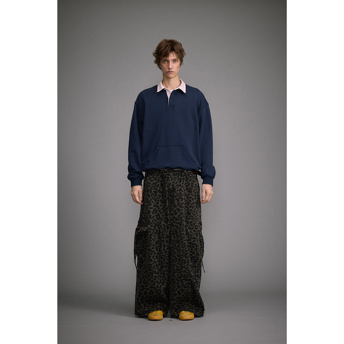 Full-length front view of a model in a navy pullover and loose dark leopard-print cargo pants.