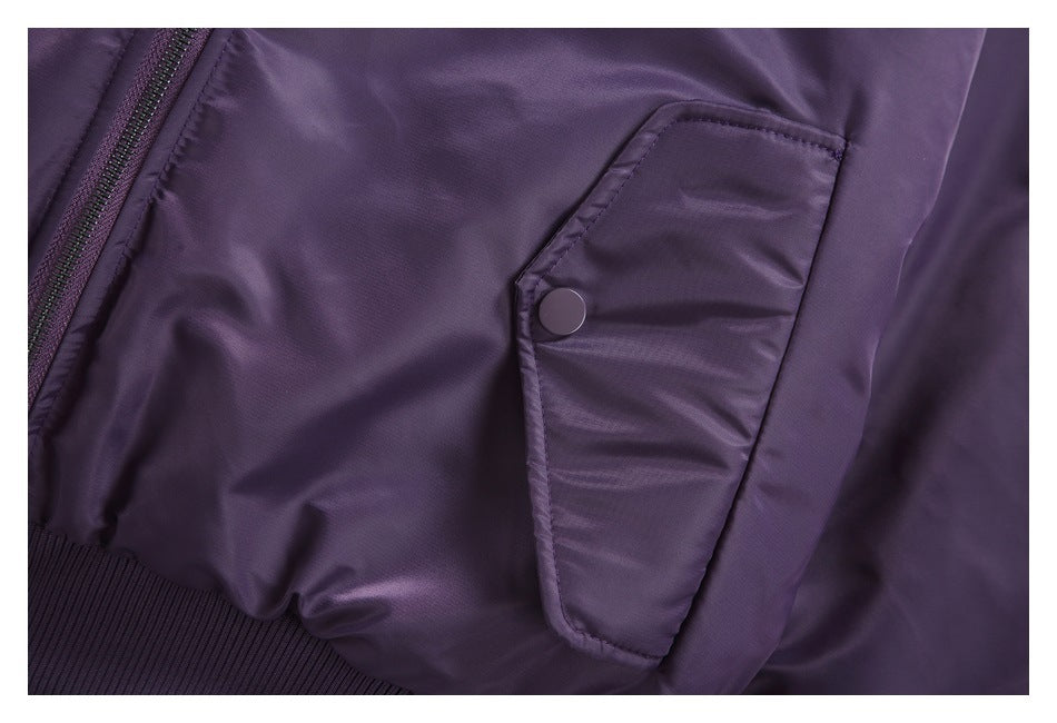 Close view of a purple jacket pocket flap with a snap button beside the front zipper.