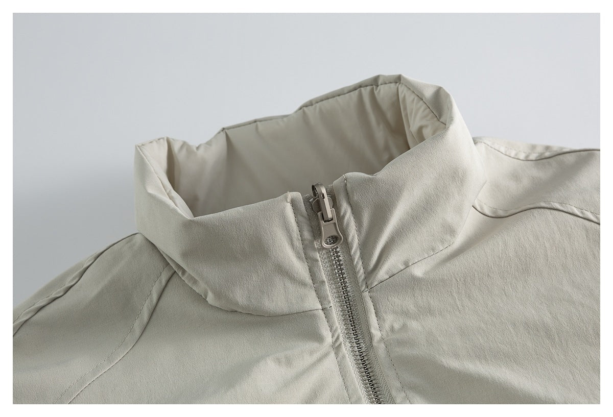 Close-up of a light beige jacket’s raised stand collar and front zipper.