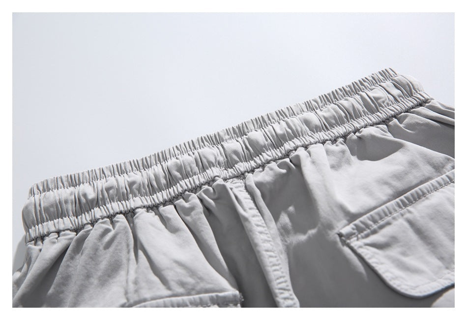 Close-up of the shorts' gathered elastic back waistband and upper edge of a flap pocket.