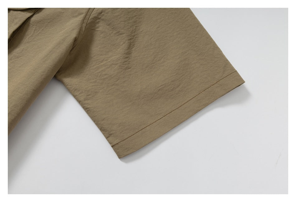 Close-up of the short sleeve and stitched cuff hem of a tan shirt.