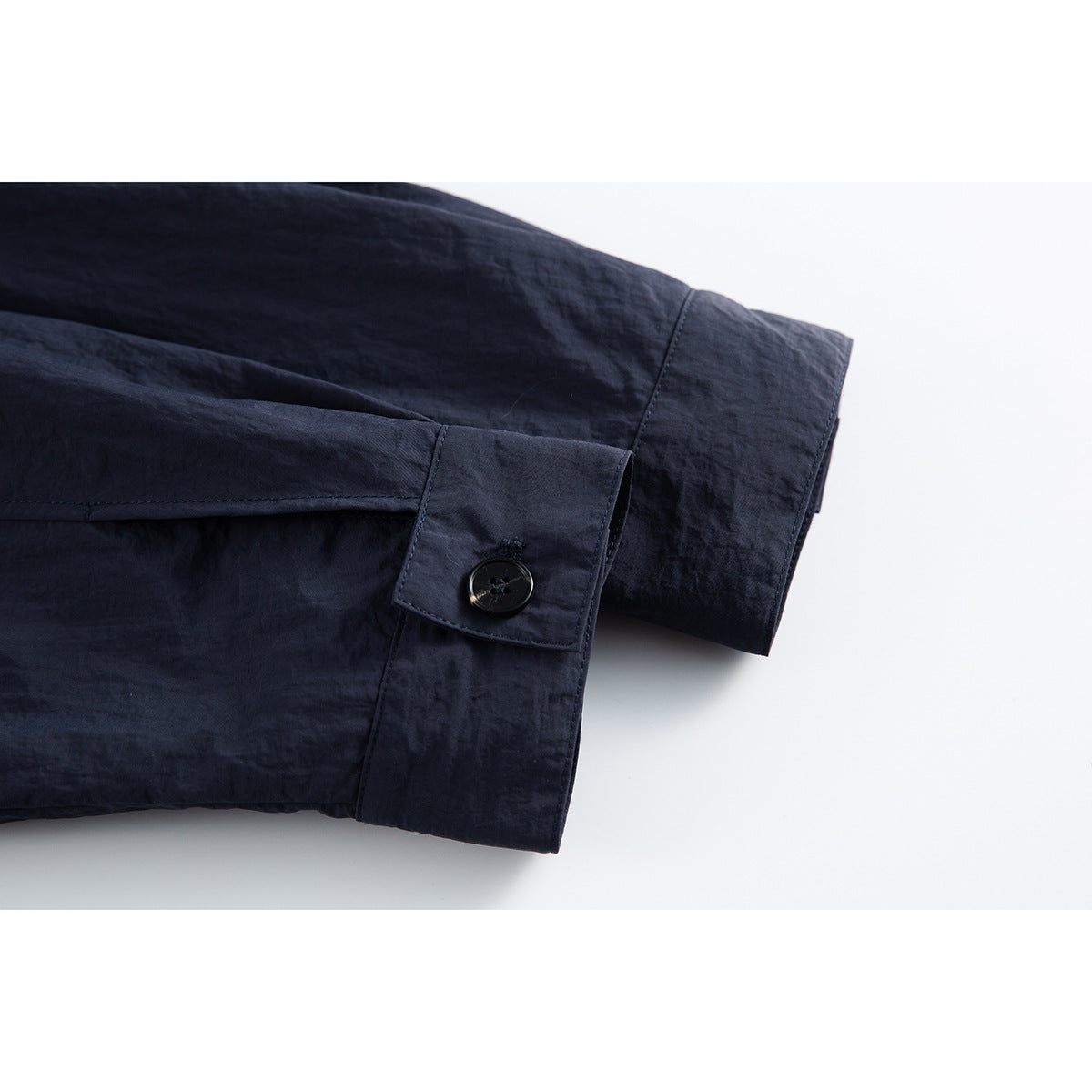 Close-up of a dark navy jacket sleeve cuff with a button and stitched placket.