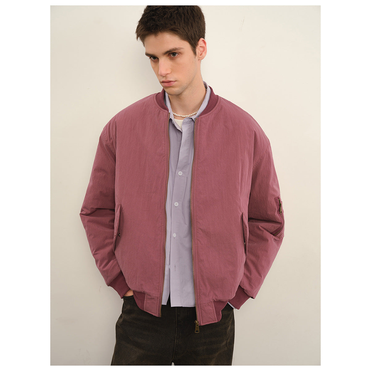Man wearing a dusty mauve zip-front bomber jacket with ribbed trim, side pockets and a sleeve utility pocket.