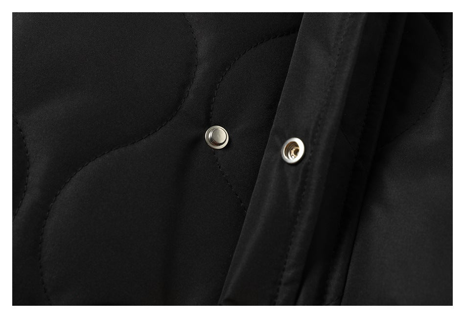 Close-up of the black quilted jacket's open placket, showing the two halves of a metal snap.
