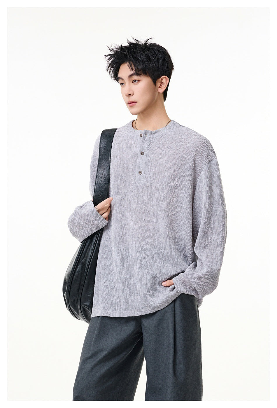 Model wearing a light gray textured long-sleeve Henley top with three buttons and dark trousers.