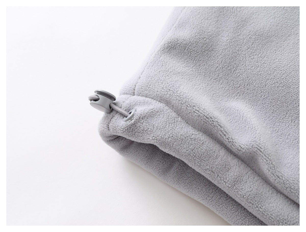 Close-up of pale gray fleece fabric with a drawcord and plastic toggle at the edge.