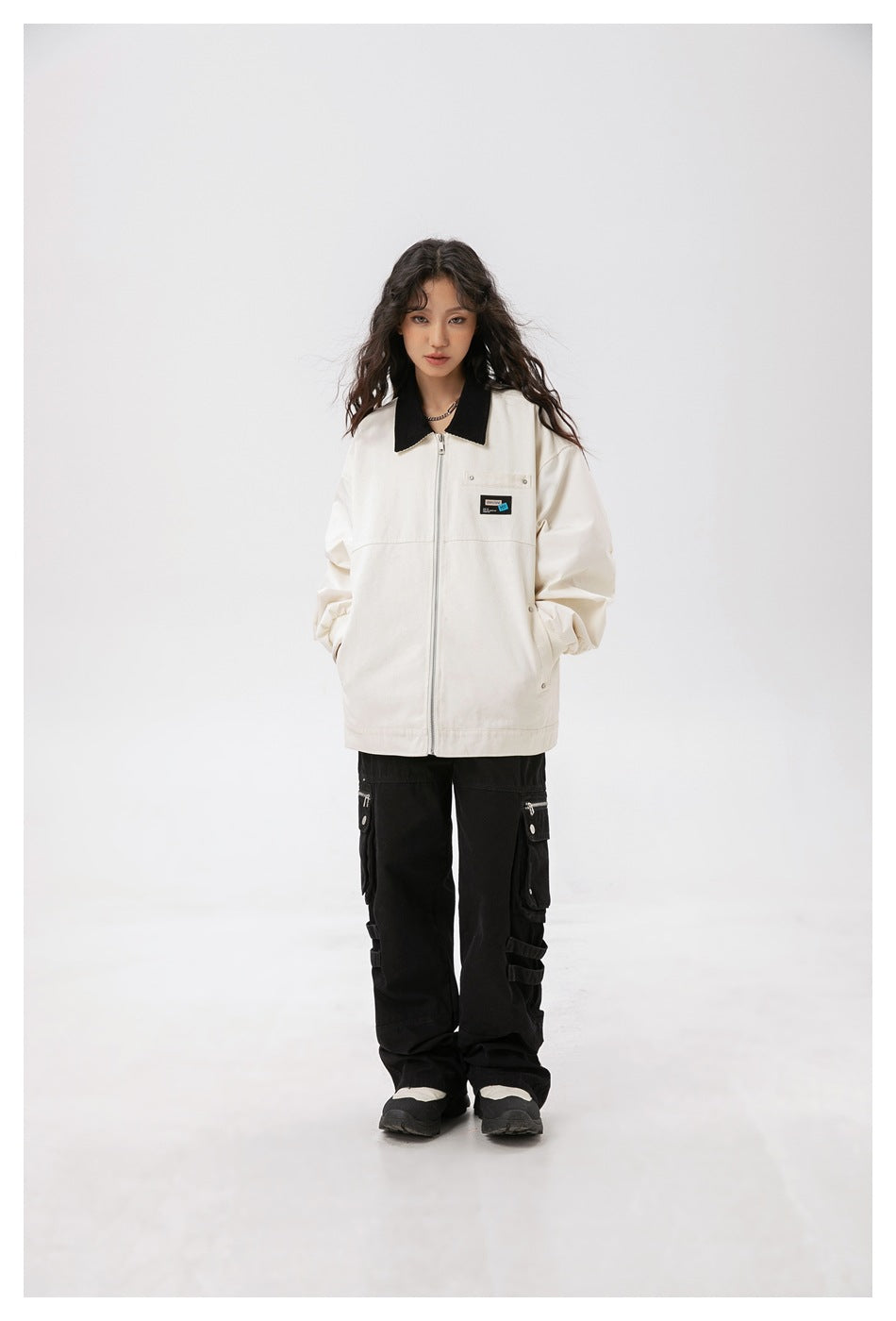 Front view of a model wearing an oversized ivory jacket with a black collar, zip closure, and chest pocket.