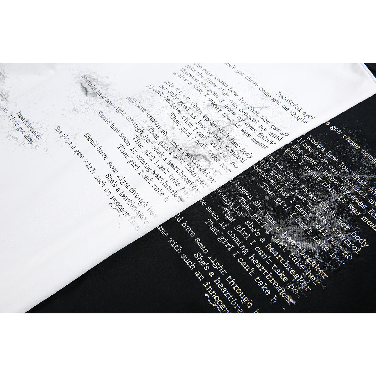 Close-up of white and black T-shirts showing distressed English text printed across the fabric.