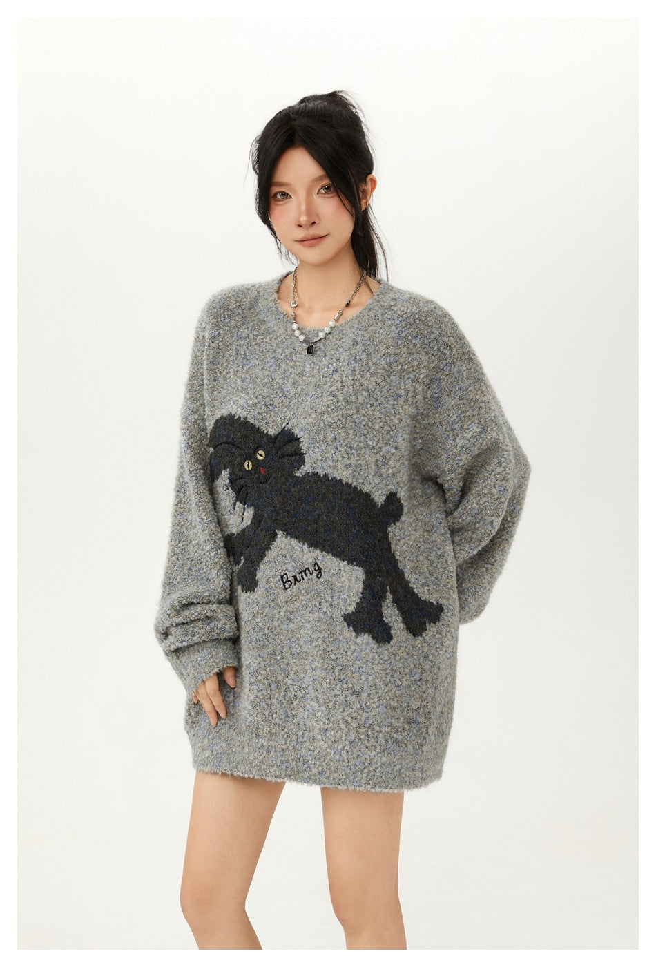 Model wearing an oversized gray-blue sweater with a large black cat graphic on the front.