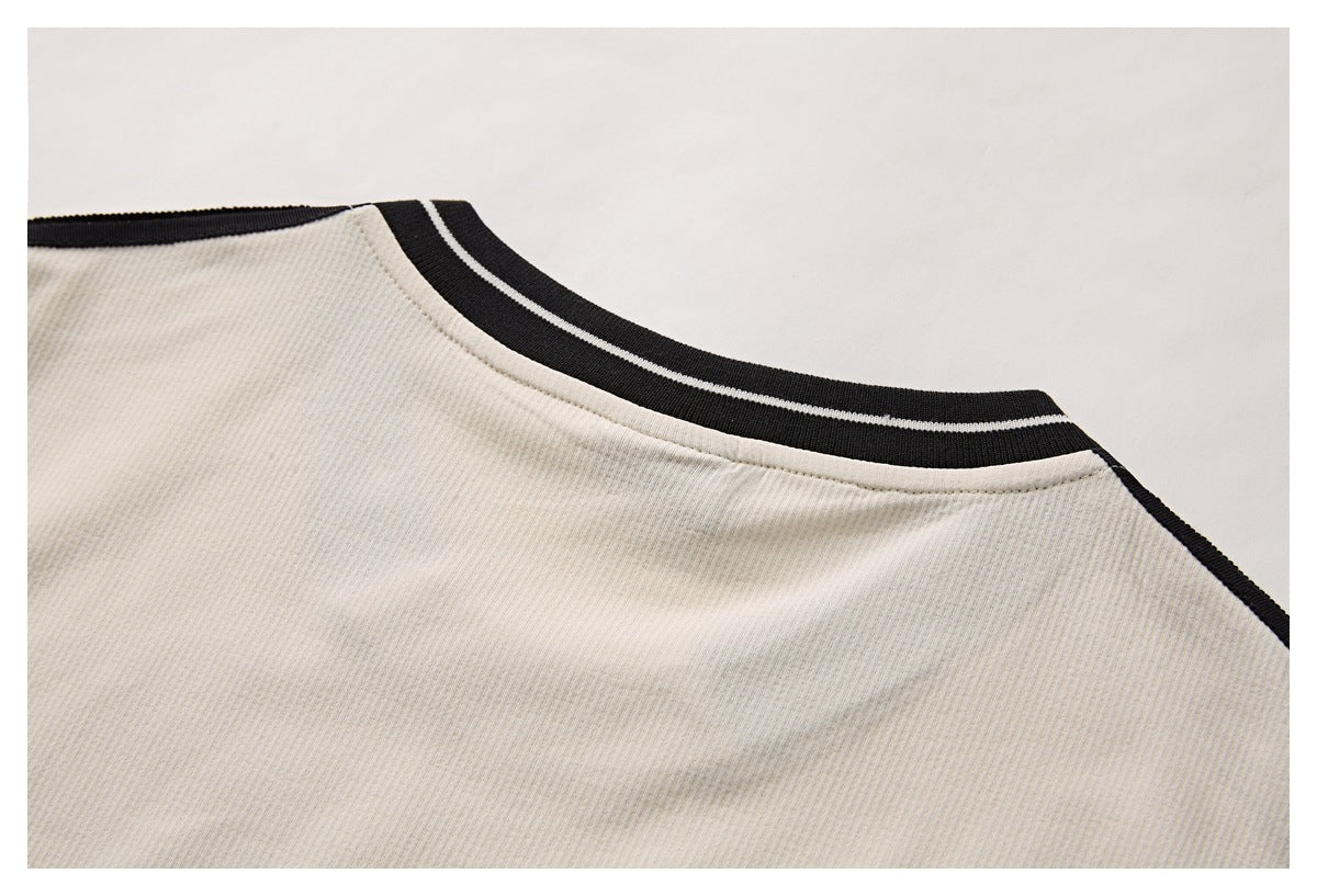 Close-up of a cream garment neckline with black ribbed trim and a thin light stripe.