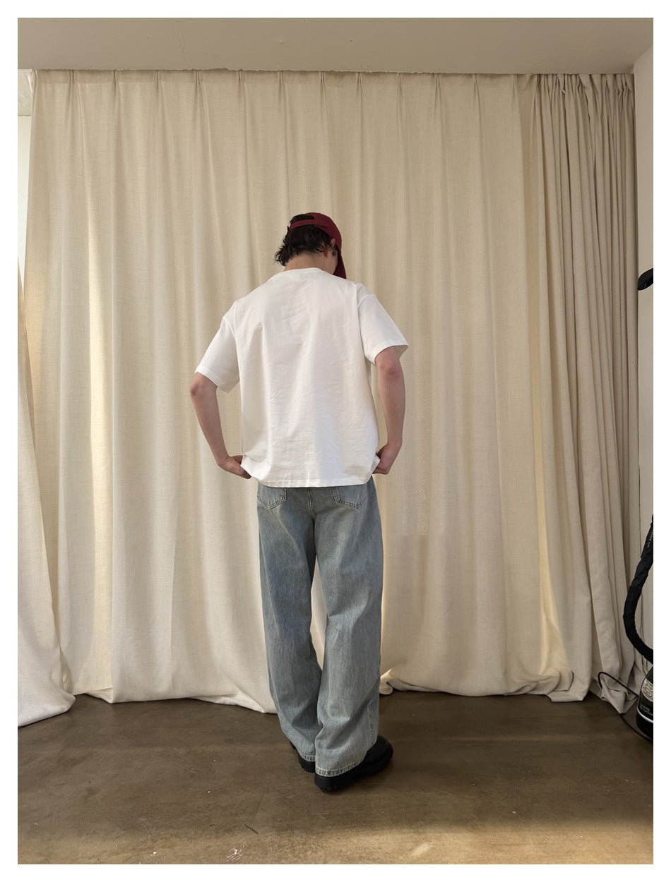 Back view of a model wearing the plain off-white T-shirt with light-wash jeans and a burgundy cap