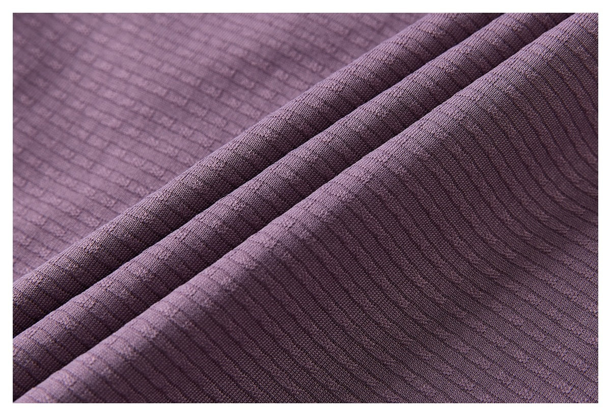 Close-up of purple ribbed fabric arranged in overlapping folds, showing its textured surface.