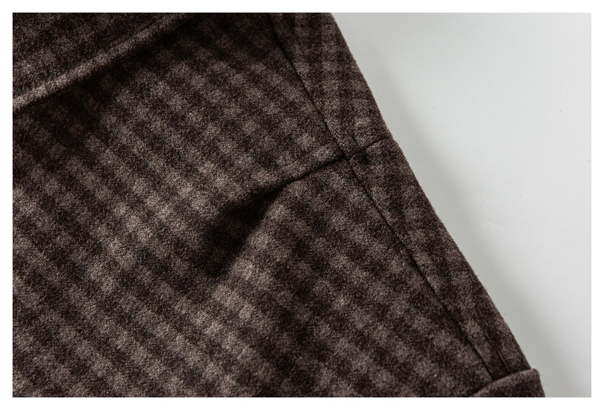 Close-up of a stitched seam and folded edge on dark brown mottled fabric.