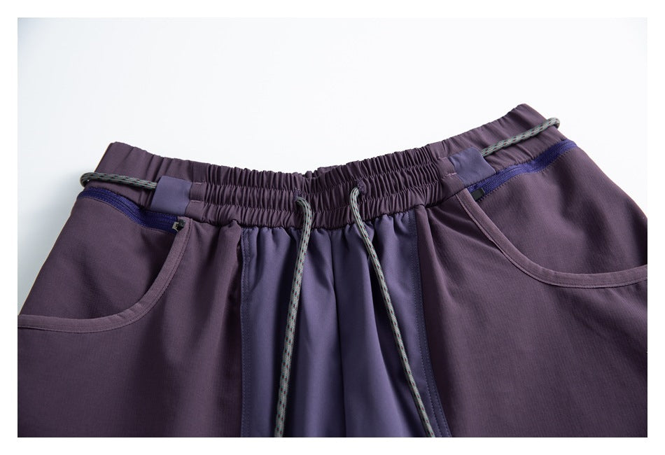 Close-up of the purple pants' elastic drawstring waist, contrast panels, and curved front pockets.